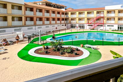 Kompleks hotelowy z basenem i wypoczywającymi gośćmi.