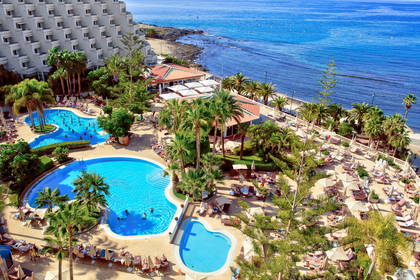 Hotel z basenami i palmami, widok z góry na ocean.