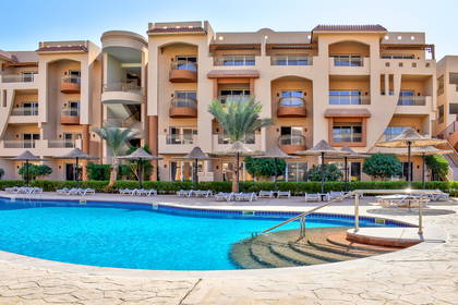 Kompleks hotelowy z basenem i parasolami.