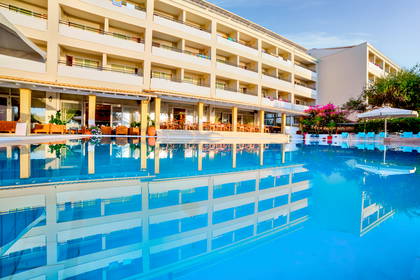 Hotel z basenem, którego budynek odbija się w wodzie.