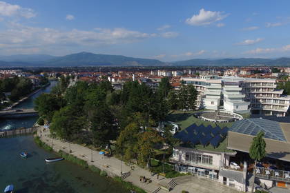Panoramiczny widok na miasto z rzeką i górami w tle.