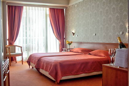 Pokój hotelowy z dwoma łóżkami, zasłonami i szampanem.