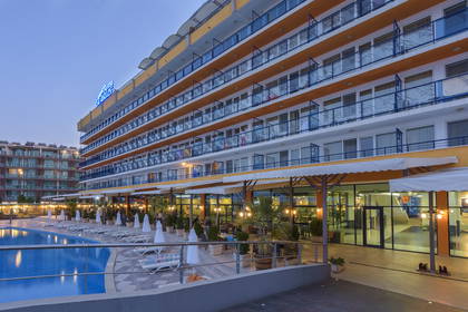 Wielopiętrowy hotel z basenem, leżakami i restauracją na zewnątrz.