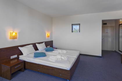 Pokój hotelowy z dużym łóżkiem i szafką nocną.