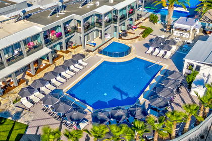 Widok z góry na basen hotelowy z leżakami i parasolami.