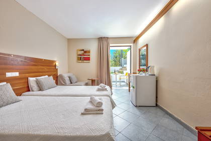 Pokój hotelowy z dwoma łóżkami, lodówką i balkonem.