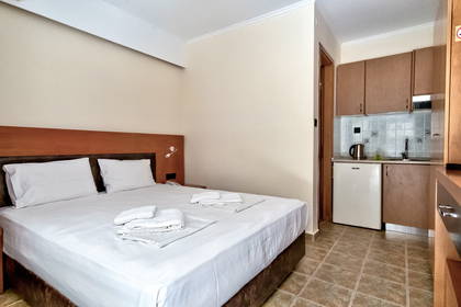 Pokój hotelowy z łóżkiem i aneksem kuchennym.