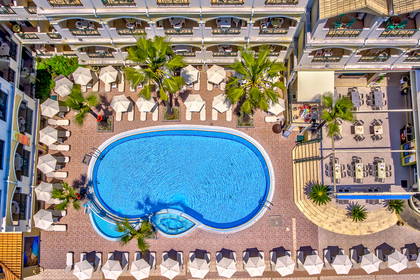 Hotel z basenem, leżakami i parasolami, widok z góry.