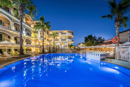 Hotel z basenem i palmami nocą.
