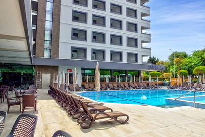 Basen hotelowy z leżakami i parasolami.