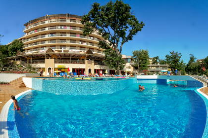 Hotel z basenem. Ludzie kąpią się i odpoczywają na leżakach.
