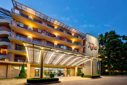 Fasada hotelu z podświetlonym wejściem i balkonami.
