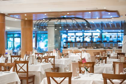 Restauracja: białe obrusy na stołach i drewniane krzesła.