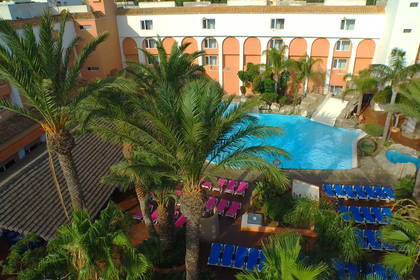 Hotel z basenem, palmami i leżakami. Widok z góry.