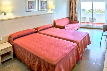 Pokój hotelowy z dwoma łóżkami, sofą i balkonem.
