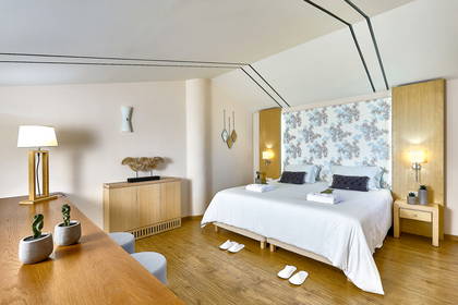 Jasny pokój hotelowy z łóżkiem, szafką nocną i biurkiem.