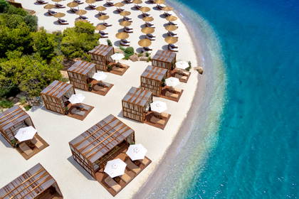 Plaża z lotu ptaka, widoczne parasole i przebieralnie.
