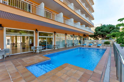 Basen hotelowy z leżakami i stolikami.