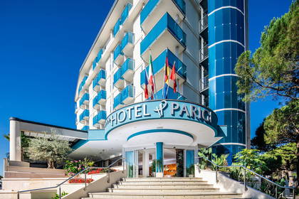 Hotel Parigina z niebieskimi balkonami i przeszkloną wieżą.