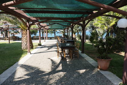 Pergola z drewnianymi stolikami i krzesłami w restauracji nad morzem.