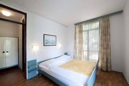 Pokój hotelowy z łóżkiem, szafą i oknem.