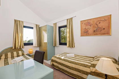 Pokój hotelowy z dwoma łóżkami, szafą i biurkiem.