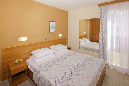 Pokój hotelowy z dużym łóżkiem, szafką nocną i lustrem.