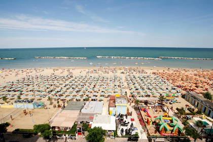 Widok z góry na plażę z parasolami i placem zabaw.
