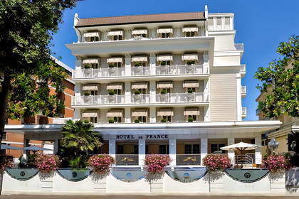 Hotel de France z balkonami ozdobionymi kwiatami.