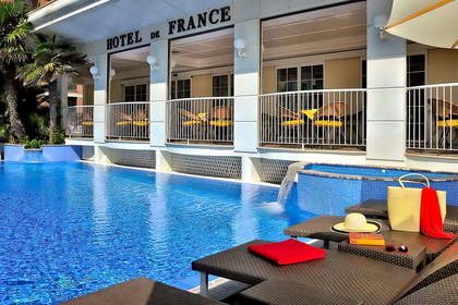Basen z leżakami przy Hotelu de France.