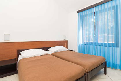 Pokój hotelowy z dwoma łóżkami i brązowymi narzutami.