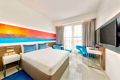 Pokój hotelowy z łóżkiem, biurkiem i krzesłami.