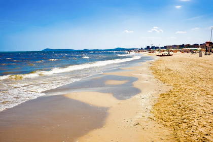 Piaszczysta plaża z budynkami w tle.