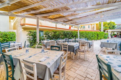 Restauracja na zewnątrz z nakrytymi stolikami pod zadaszeniem.