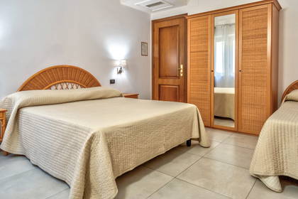 Pokój hotelowy z dwoma łóżkami, szafą i drewnianymi drzwiami.