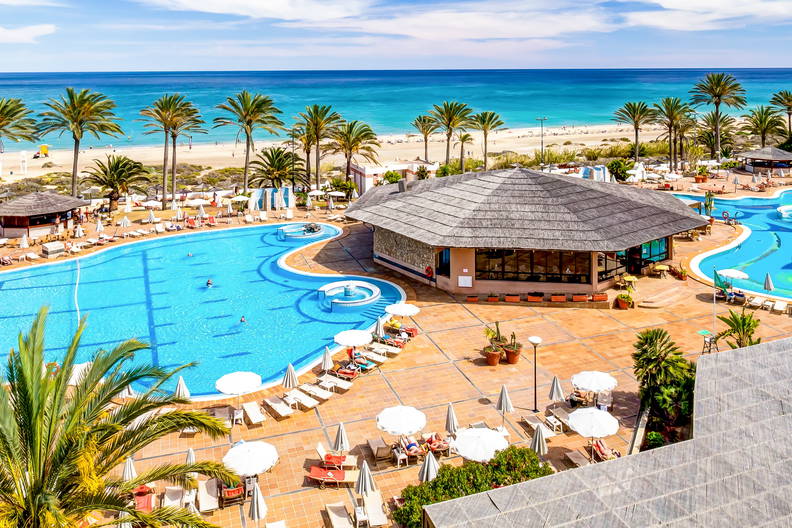 Hotelowy basen z palmami, widok z góry. W tle plaża.