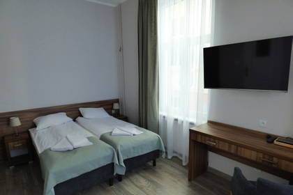 Pokój hotelowy z dwoma łóżkami, biurkiem i telewizorem.
