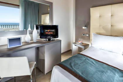 Pokój hotelowy z biurkiem, telewizorem i łóżkiem.
