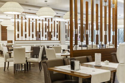 Elegancka restauracja z drewnianymi panelami i stylowymi lampami.