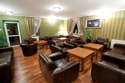 Salon z brązowymi skórzanymi fotelami i drewnianymi stolikami kawowymi.