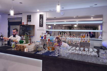 Bar z dwoma barmanami przygotowującymi koktajle.