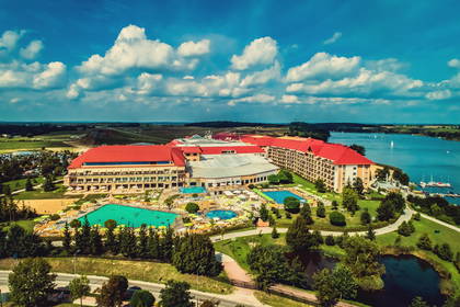 Hotel z basenami widziany z góry, w tle jezioro.