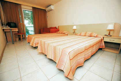 Pokój hotelowy z dwoma łóżkami i pomarańczową sofą.