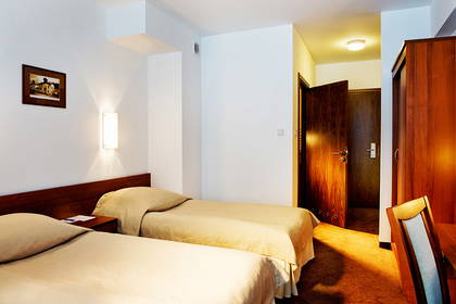 Pokój hotelowy z dwoma łóżkami, szafą i otwartymi drzwiami.