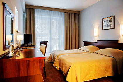 Pokój hotelowy z dwoma łóżkami, biurkiem i oknem.