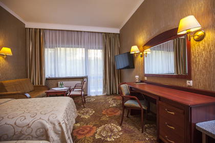 Pokój hotelowy z łóżkiem, biurkiem i kanapą.