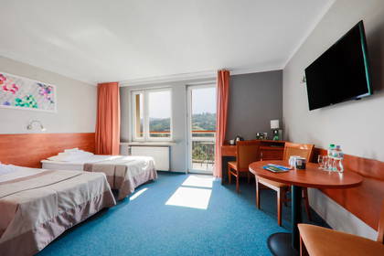 Pokój hotelowy z dwoma łóżkami, biurkiem i stolikiem.