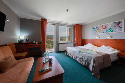 Pokój hotelowy z łóżkiem, sofą, biurkiem i balkonem.