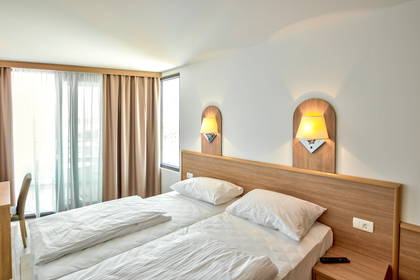Pokój hotelowy z dwoma łóżkami i lampkami nocnymi.