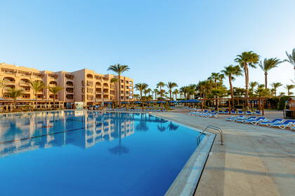 Kompleks hotelowy z basenem otoczonym palmami.